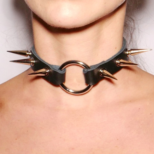 Collier ras-le-cou en cuir noir orné de pics en acier argenté. Il habille le cou dans un esprit fetish.