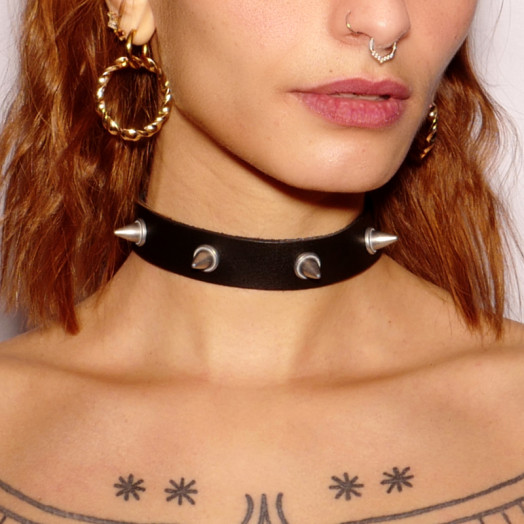 Collier ras-le-cou en cuir noir orné de pics en acier argenté. Il habille le cou dans un esprit fetish.