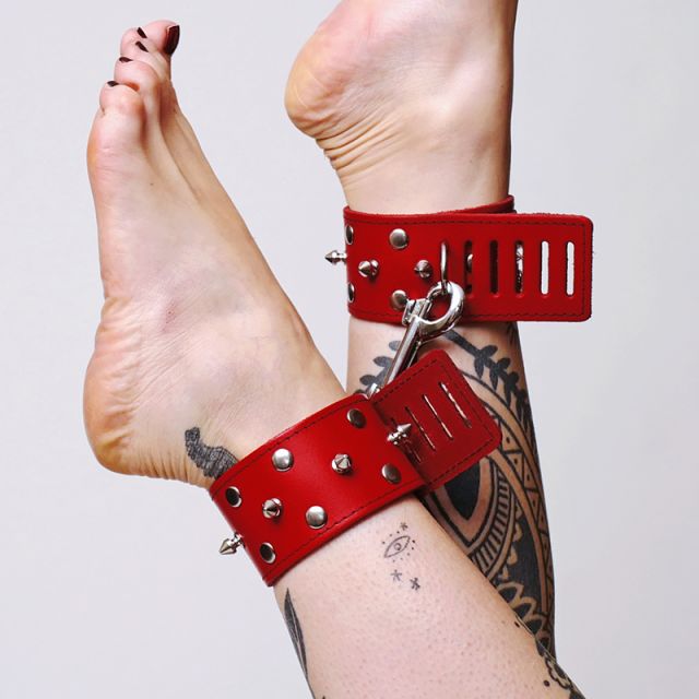 Une paire de chevillères en cuir rouge avec pics et mousqueton en acier pour plus de fermeté et de sensations.